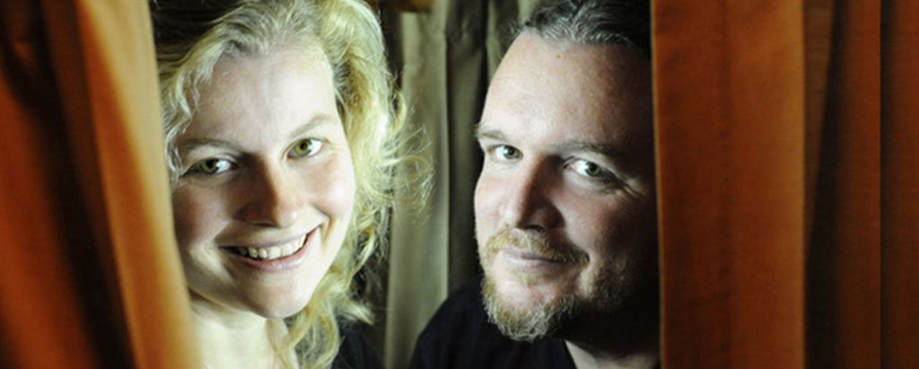 portrait of woman and man peaking through theater curtains