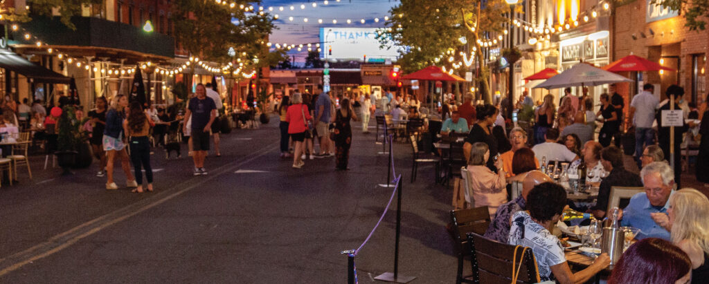 people enjoying dinner and walking through Red Bank's Broadwalk at night