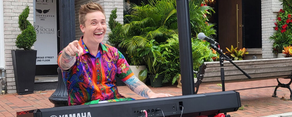 person in a colorful shirt playing keyboard and singing along Broad Street